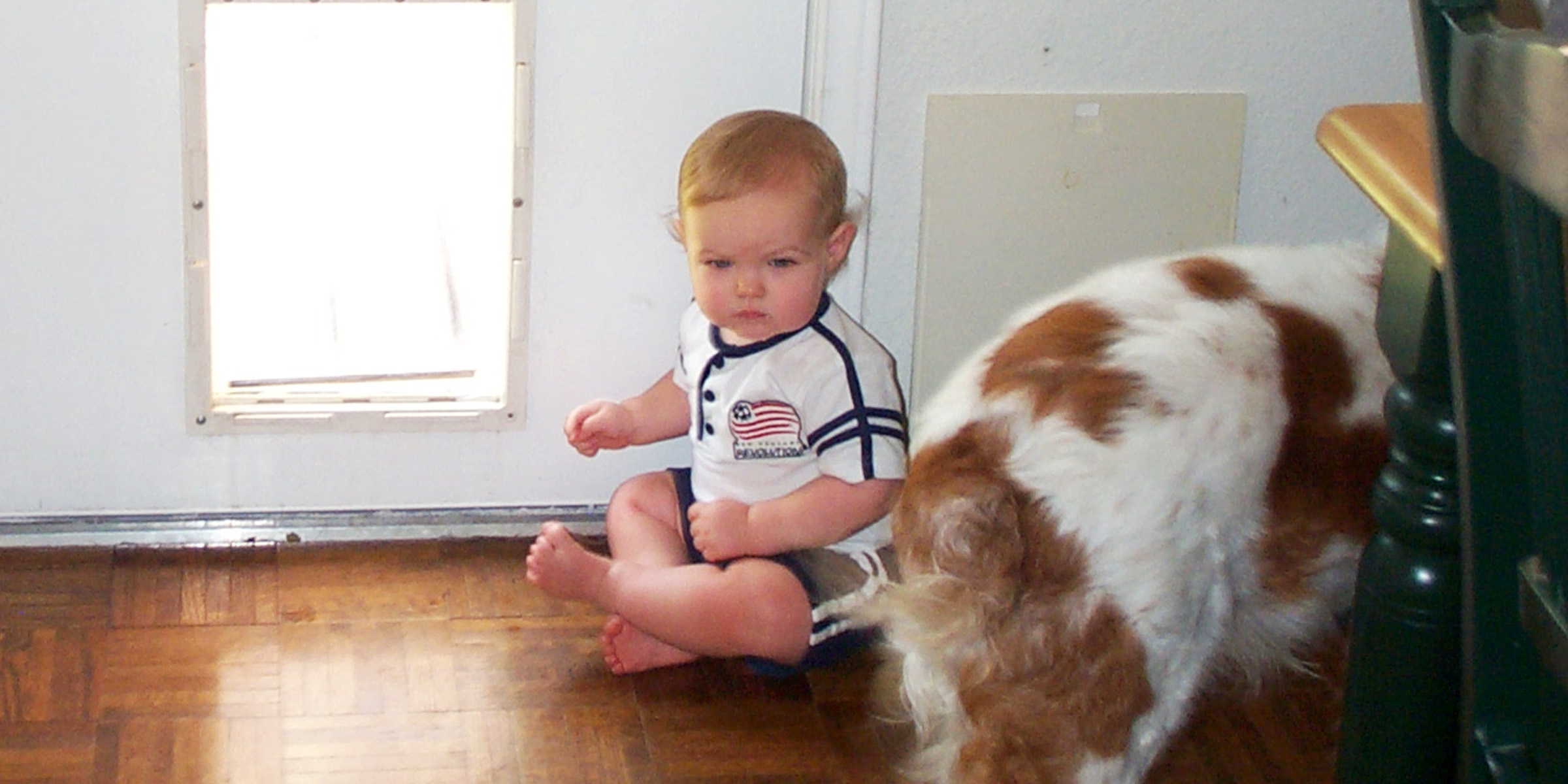 Un enfant assis à côté d'une porte pour chien | Source : Flickr